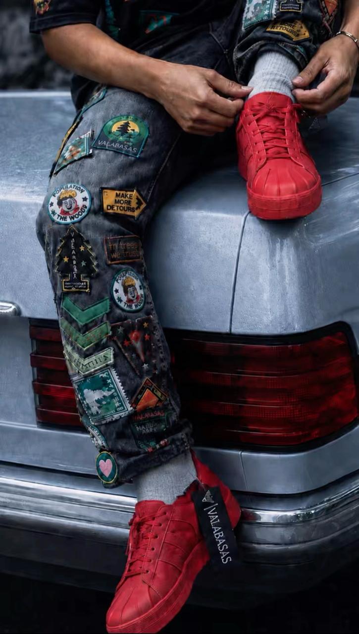 SHIFT — patched denim trousers and red sneakers on car